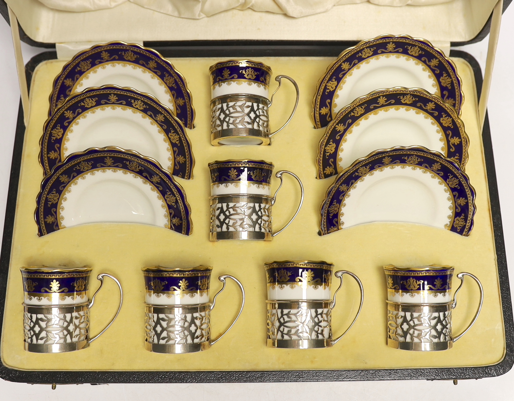 A cased George V set of six Aynsley coffee cans and saucers, the cans with pierced silver holders, C.S. Green & Co, Birmingham, 1924, can 57mm.